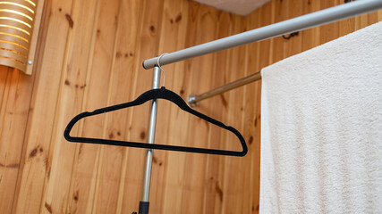 Empty black hanger and white towel in wooden room