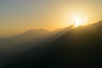 Beautiful sunset casting warm colors over the rugged peaks of Svaneti, Georgia, creating a serene and atmospheric mountain landscape.