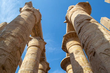 Egypt, Luxor, 01.02.2022.Tall ancient Egyptian temple columns decorated with colorful hieroglyphs and painted figures illuminated by bright sunlight, creating a warm historic atmosphere.