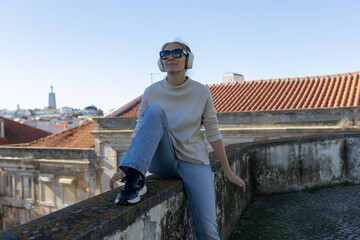 Young woman enjoying music with headphones overlooking lisbon city