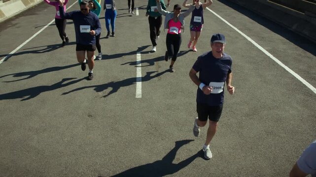 A group of enthusiastic runners participate in a marathon race on a sunny day. They show joy and accomplishment, celebrating their fitness journey on the open road.