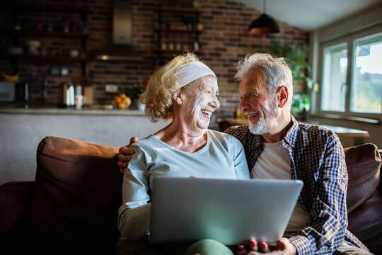 Senior couple laughing with laptop on sofa at home