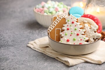 Christmas treat. Tasty gingerbread cookies, marshmallows and burning candles on grey table, closeup. Space for text