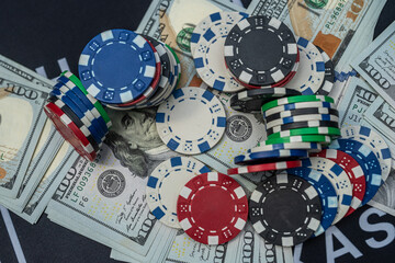 Casino poker chips on US hundred dollar bills representing gambling, luck, risk and financial winnings