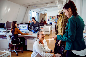 Young adult women smiling during fashion fitting in design studio