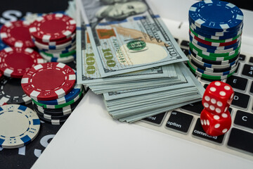 Poker chips, dice and laptop with dollar bills symbolizing online gambling, risk, money and casino success