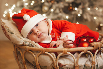 Little girl lays on a holiday background in Santa costume