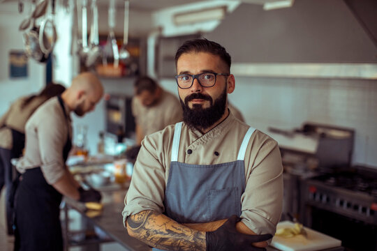 Adult male chef standing confident in professional restaurant kitchen