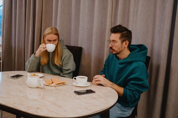 A young man and his female friend chat over tea in a cozy kitchen. Authentic moment of casual conversation and friendly connection in everyday setting
