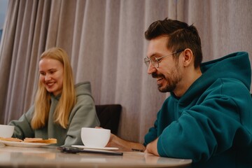 A young man and his female friend chat over tea in a cozy kitchen. Authentic moment of casual conversation and friendly connection in everyday setting