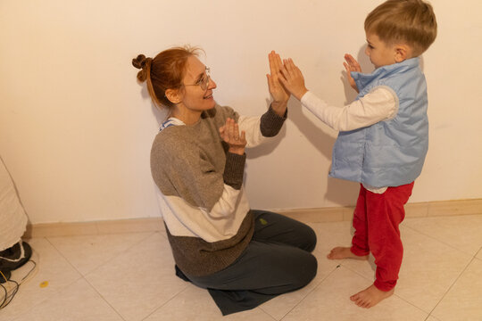 Mother and child playing clapping game at home