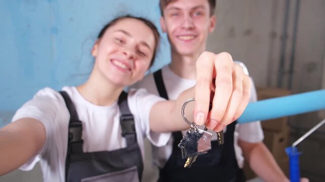 Own home. Mortgage relocation concept. Happy couple holding key from new first house. Family celebrating moving day. Husband wife customers buyers purchase real estate hold moving box showing keys