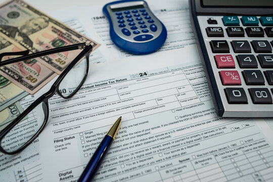 US dollar bills and form 1040 with glasses and calculator ready for 2026 tax processing - Powered by Adobe