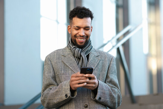 Smiling man in suit with smartphone on city street