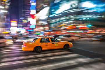 Yellow cab speeds through Times Square at night in Manhattan