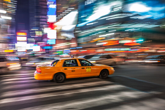 Yellow cab speeds through Times Square at night in Manhattan