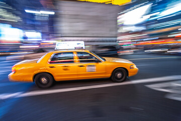 Yellow cab zooms by in Times Square at night
