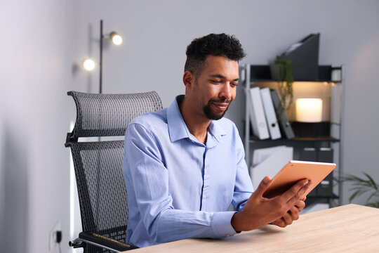 African-american man using tablet at wooden table indoors