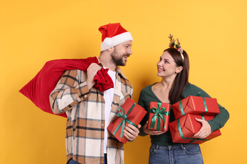 Happy couple with Christmas gifts on yellow background