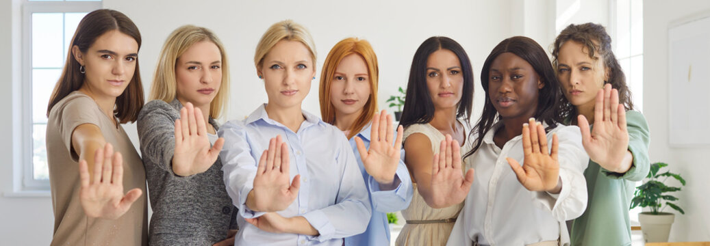Women group show stop gesture in solidarity. A diverse team stands united, raised palms signaling refusal and warning against harassment, promoting safety and respect. A clear message say no.