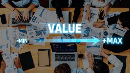 Professionals engage in a collaborative meeting analyzing data and charts on a wooden table, showcasing strategies for value maximization and business growth. Raster