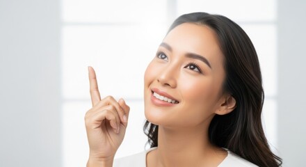Confident young woman with a bright smile pointing upwards in a modern bright indoor setting