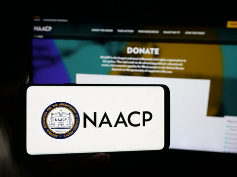 Stuttgart, Germany - 11-19-2025: Person holding smartphone with logo of US colored people association NAACP on screen in front of website. Focus on phone display.