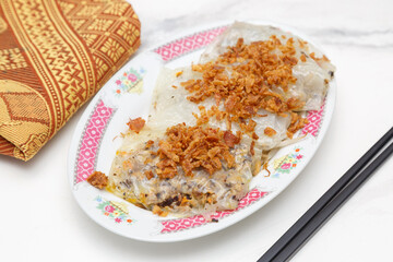 Raviolis vietnamiens (Banh Cuon) au porc à la vapeur parsemés d'oignons frits dans une vaisselle traditionnelle. Cuisine vietnamienne