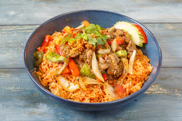 Khao Pad au bœuf et basilic dans un bol bleu, cuisine thaïlandaise, fond bleu rustique
