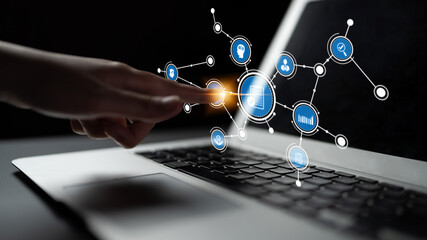 A hand is poised to interact with a laptop screen, showcasing digital icons that symbolize technology, innovation, and connectivity in a modern workspace. Tessel