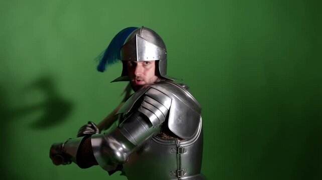Medieval knight in silver armor swinging large battle axe action on green screen background video footage