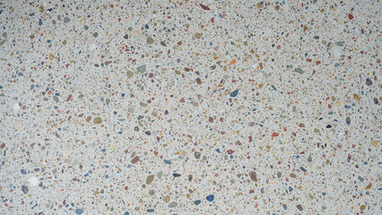 Close-up texture of a light terrazzo surface with multicolored stone fragments embedded in cement