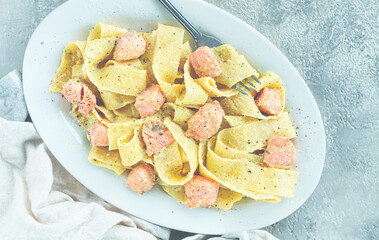 papardelle pasta, in creamy sauce with salmon, homemade, on a gray background, no people,