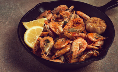 Fried shrimps, in a cast-iron pan, shrimps for beer, in a newspaper, on a gray table, there are no people,