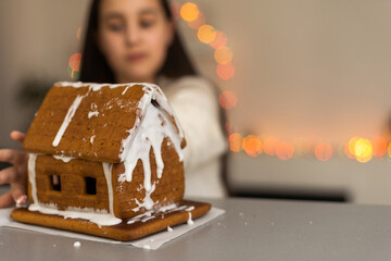 gingerbread house. little girl in holidays preparations putting glazing on gingerbread house Christmas trees.