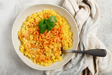 risotto with shrimp, in a bowl, on a textured surface, with a side dish of fresh coriander, homemade, no people,