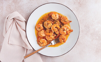 Savory shrimp dish served in a white plate with flavorful sauce and herbs