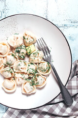 homemade dumplings, on a plate, with herbs on a rustic table