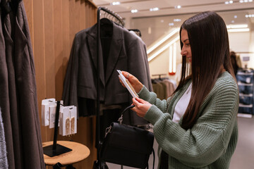 Young brunette woman choosing festive accessories in a fashion store, holding elegant earrings and enjoying Christmas holiday shopping atmosphere