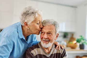 Portrait of a happy senior couple embracing hugging and having fun at home
