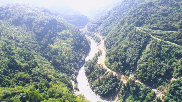 Aerial drone forward over step farms on Himalayas to blue waters of Ganga river with a dam blocking the flow to provide hydel power at Chopta Tungnath Uttarakhand India