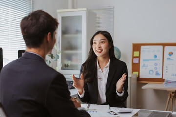 Confident Asian businesswoman discussing business with a male client, collaborating and exchanging ideas in a professional office setting
