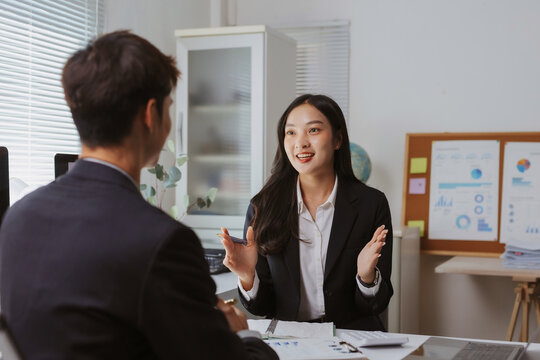 Confident Asian businesswoman discussing business with a male client, collaborating and exchanging ideas in a professional office setting