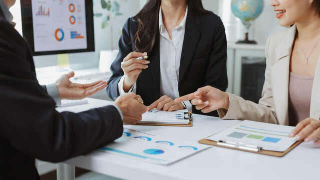 Business team collaborating and discussing financial reports with charts and graphs, analyzing data during a corporate meeting