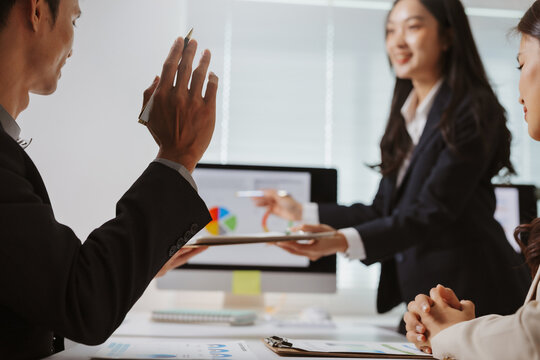 Business colleagues working together in an office, discussing financial data and analyzing charts on a computer screen