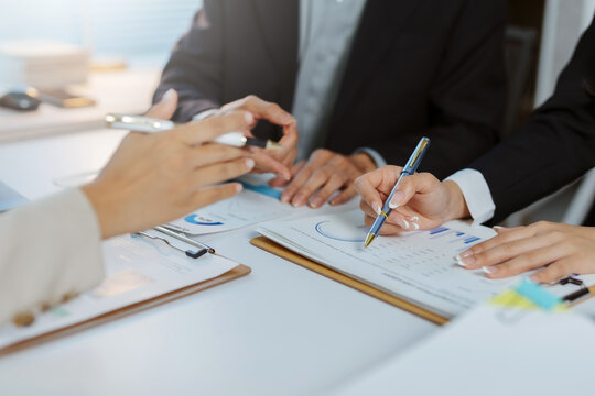 Business colleagues collaborating on a project, analyzing financial reports, charts, and graphs in an office setting