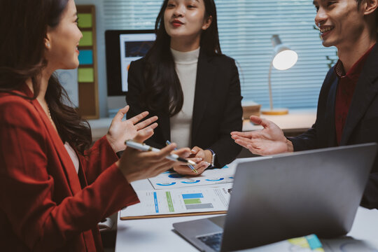 Asian business professionals collaborating on strategy, analyzing charts and data, fostering teamwork and corporate discussion