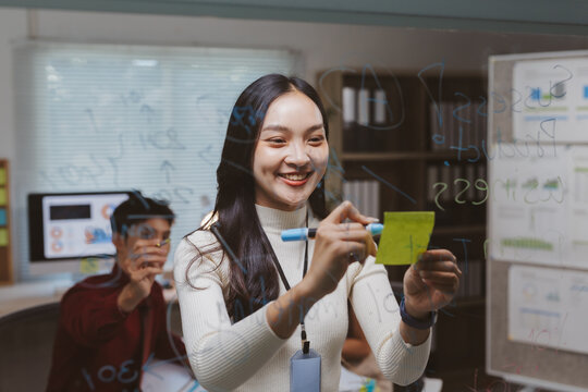 Young Asian woman smiling, collaborating and developing new strategies for a startup business meeting in the office