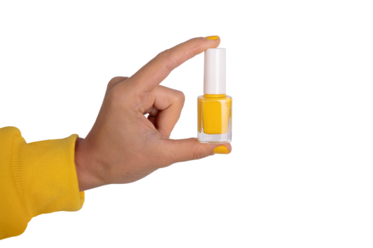 Close-up of a hand holding a bottle of yellow nail polish on transparent. Bright, modern concept for beauty, cosmetics, and manicure themes.