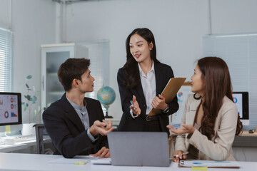 Young Asian business professionals discussing project data, sharing ideas, and working together in modern office environment